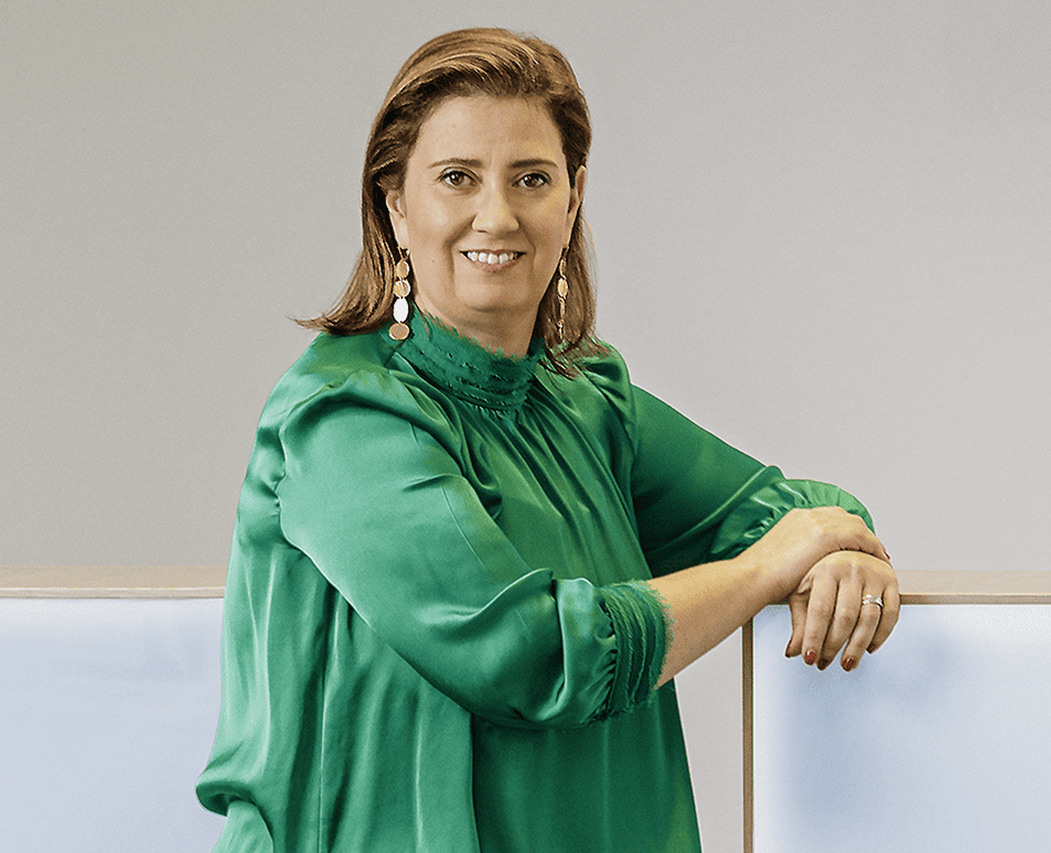 Uma mulher profissional com uma blusa de seda verde vibrante e brincos marcantes.