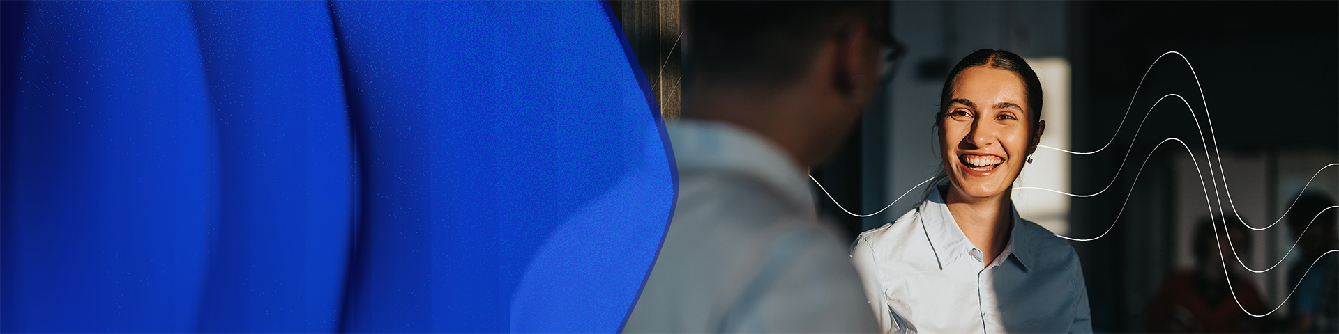 Profissionais em interação num ambiente de escritório, com elementos gráficos ondulados da identidade Hays.