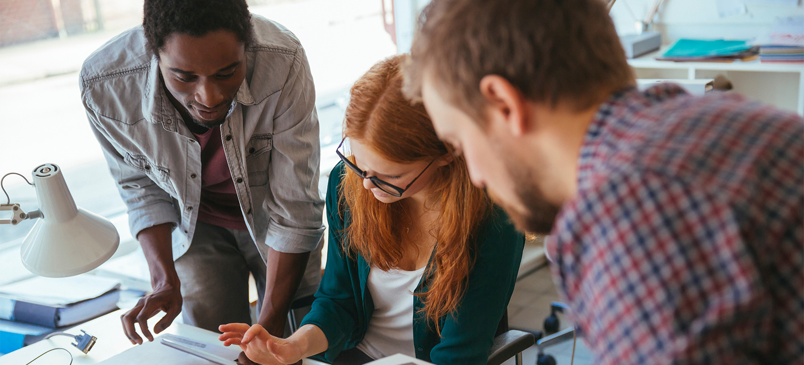 Equipa a colaborar num espaço de trabalho, reunida em torno de documentos e notas em secretária.